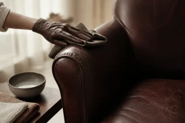 Comment nettoyer fauteuil cuir : main essuie l’assise en cuir avec microfibre humide